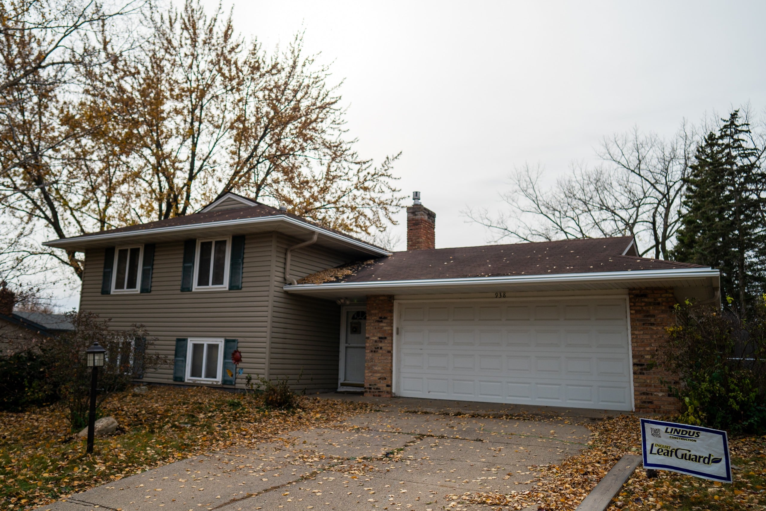 A newly installed gutter on a home in the fall with leaves on the ground.