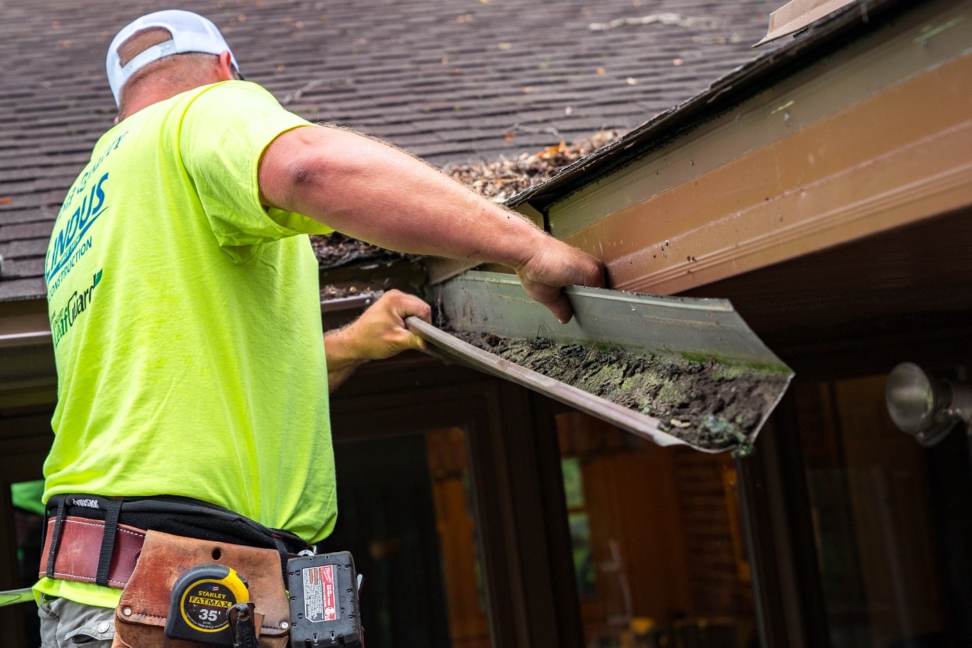 Lindus construction worker removing clogged gutters from a home
