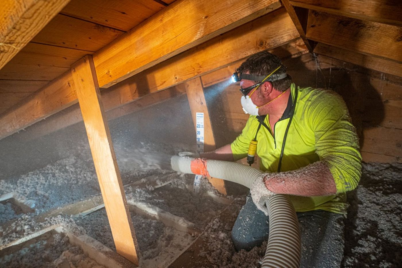  Lindus Construction team member installing blown-in insulation in a home