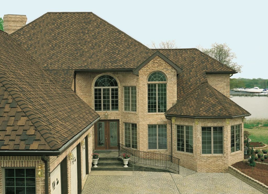 Large Brick Lake Home With Brown Shingle Roof