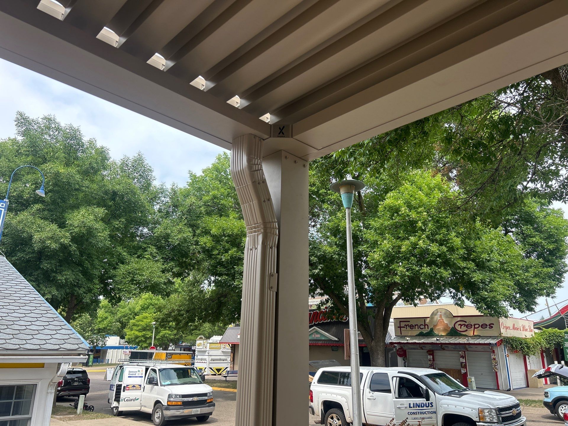 View from beneath the StruXure Pergola X at the WCCO Radio booth at the Minnesota State Fair, showing the adjustable louvers and integrated drainage system.